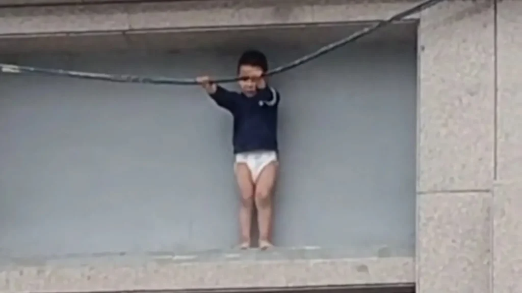 Dramatic moment: Scared 3-year-old boy clings to cable on small ledge 33 feet above ground, shopkeeper pulls him out to safety